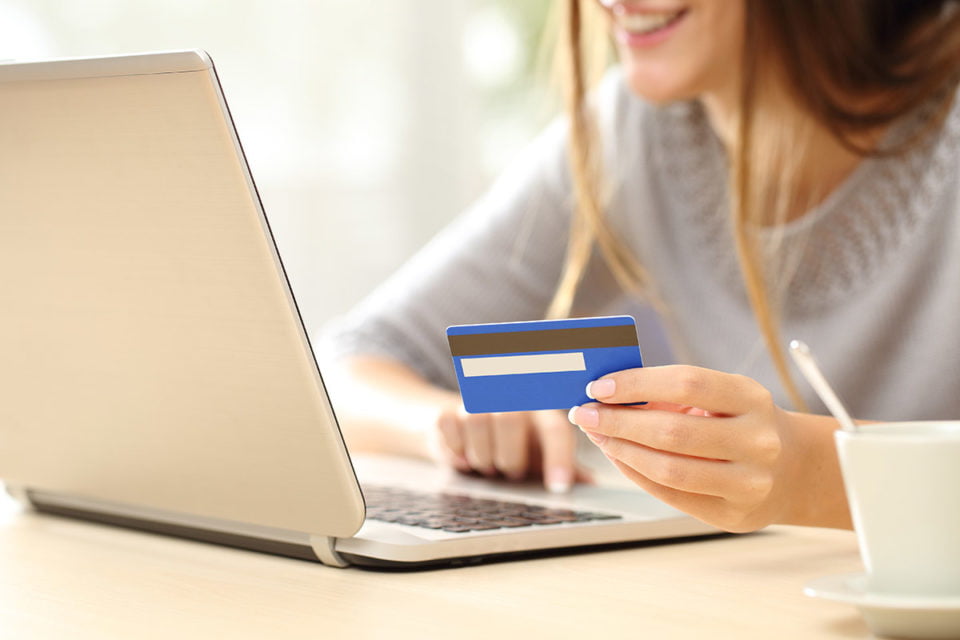 Close up of a happy woman hand buying online with a laptop and paying with a credit card